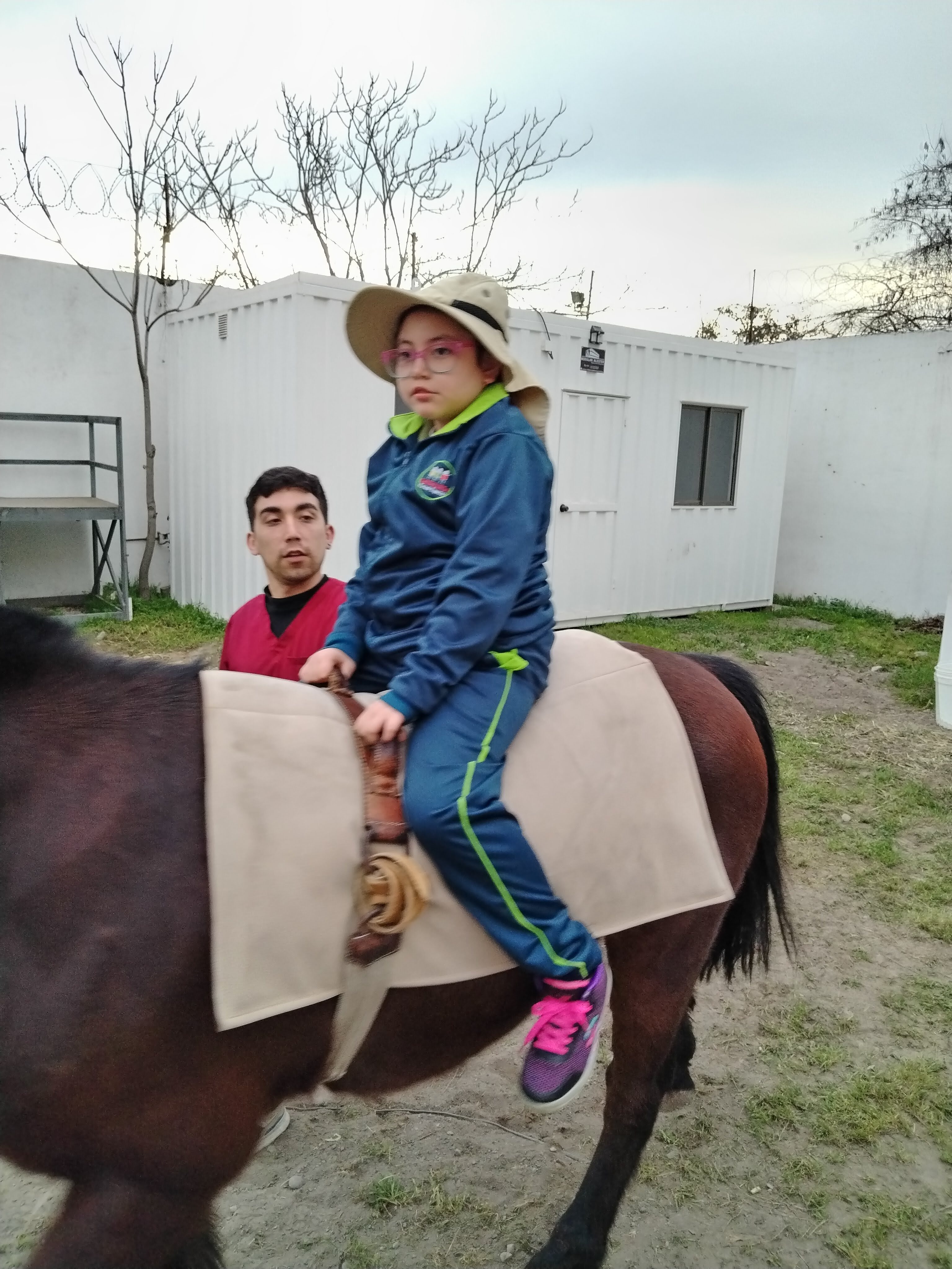 Estudiante en sesión de hipoterapia con acompañamiento del equipo